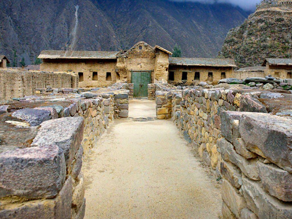 Callejón de piedra inca en Ollantaytambo, con una puerta de madera al fondo.